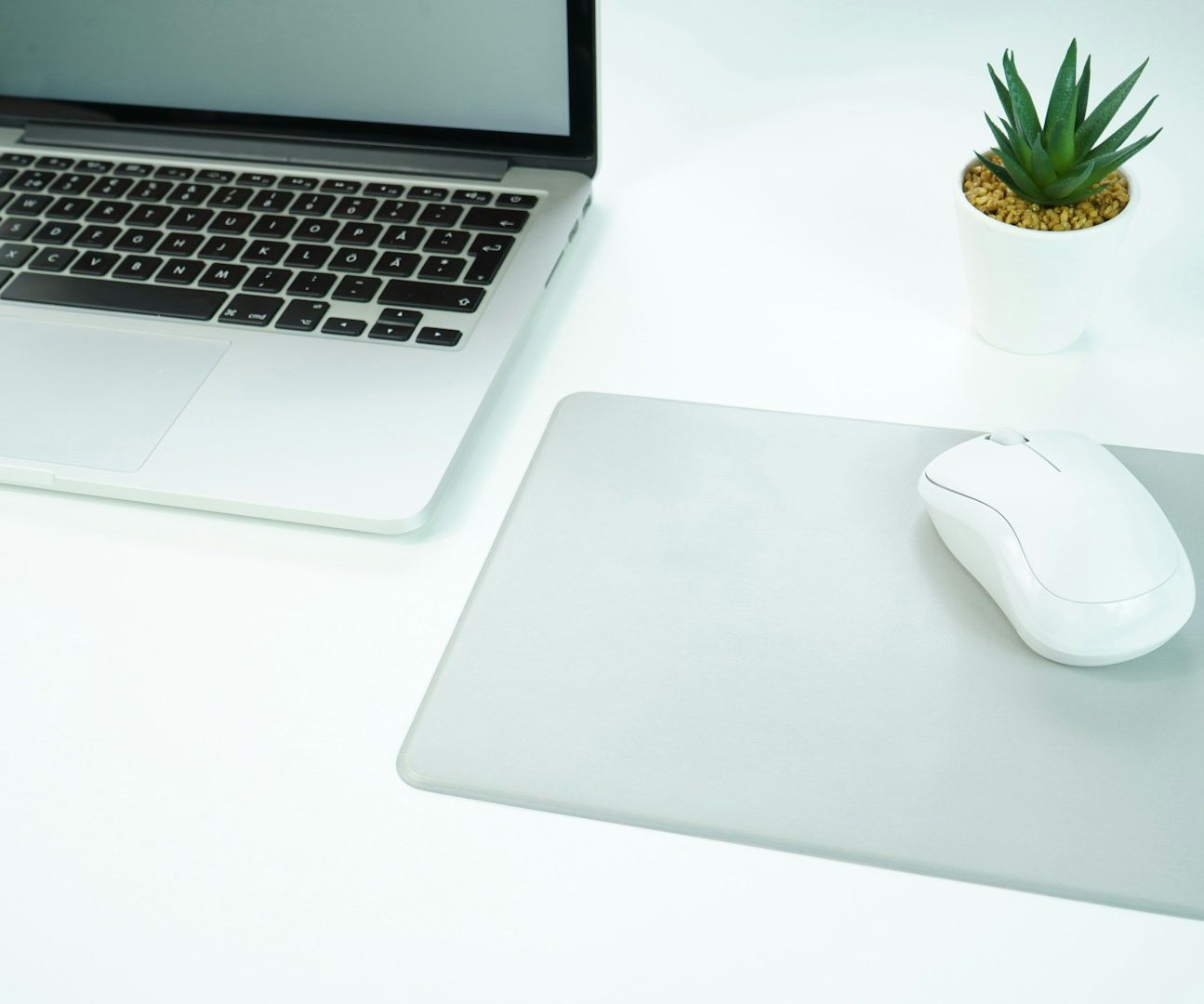 Aufgeräumter Schreibtisch mit Laptop als Symbol für digitale Unterstützung.