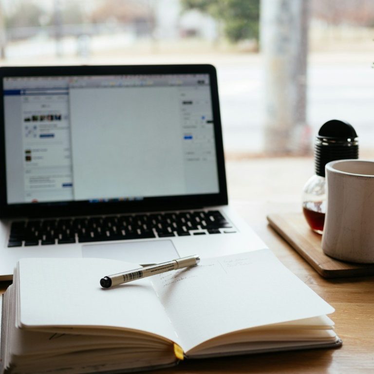 Aufgeräumter Arbeitsplatz mit Laptop und Notizbuch – Darstellung flexibler, individueller Unterstützung im Büroalltag.